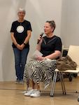 Sitzend Behindertenbeauftragte Daniela Maier, im Hintergrund stehend Angela de Soto